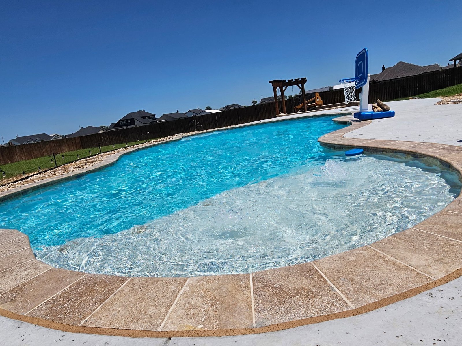 A custom gunite pool with travertine decking and spa overflow — GoodTimes Gunite Pools, Johnson County TX.